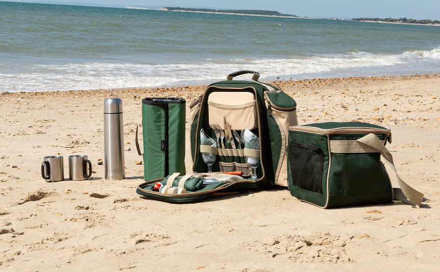 backpack hamper, cool bag, picnic blanket & flask on beach by the sea