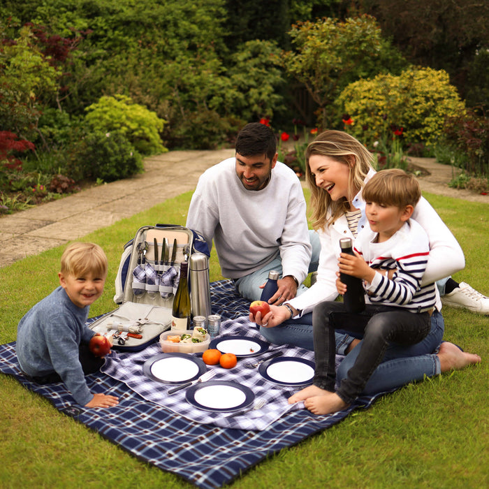 family having picnic on picnic blanket with backpack hamper